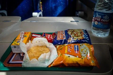 Packaged snacks and pastry on train tray table with water bottle Stock Photos