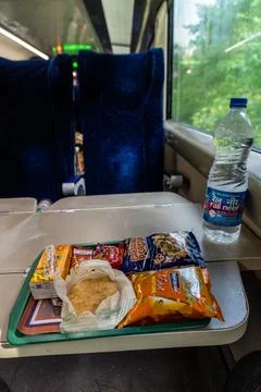 Packaged snacks and pastry on train tray table with water bottle Stock Photos
