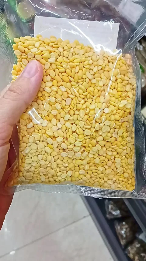 Packaged split yellow mung beans held in hand at grocery store Stock Footage 337241819