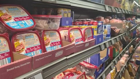 Packages of assorted meat products on a multi-level refrigerated display case in Stock Photos