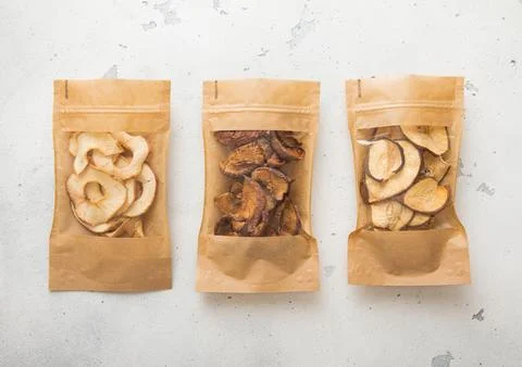Packages of assorted sweet dried apple chips and slices on light background. Stock Photos