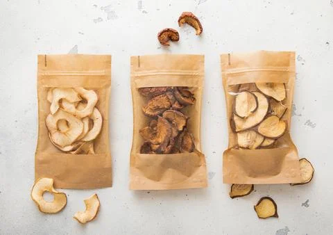 Packages of assorted sweet dried apple chips and slices on light background. Stock Photos