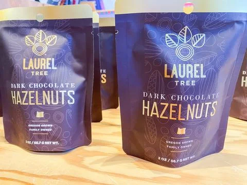 Packages of Laurel Tree Dark Chocolate Hazelnuts displayed on a wooden shel.. 스톡 사진