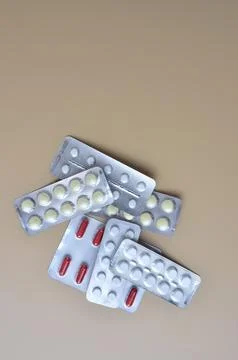 Packages of multi-colored tablets on a beige background. Stock Photos