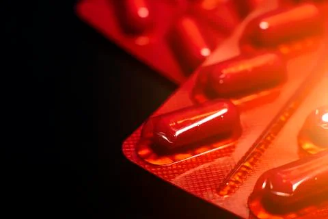 Packages of tablets in a red wrapper on a black background. Stock Photos