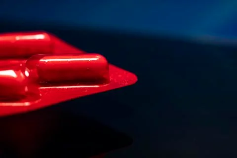 Packages of tablets in a red wrapper on a black background. Stock Photos