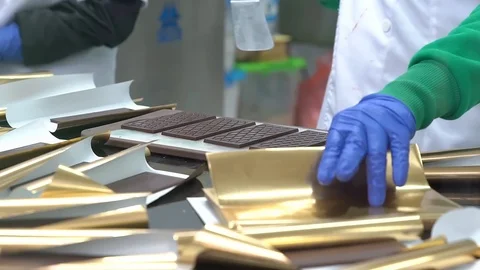 Packaging chocolate bars in wrappers by hand in factory. Stock Footage 88936450