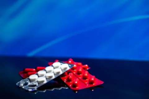 Packaging of red and white tablets on a blue background. Stock Photos