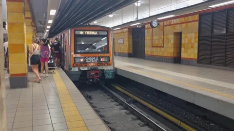 Packed Athens metro during summer, commuters jostle to board a graffiti-covered Stock Footage 319808249