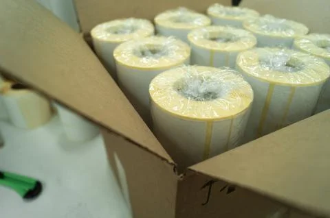 Packed in a cardboard box rollers of white self-adhesive labels for product Stock Photos