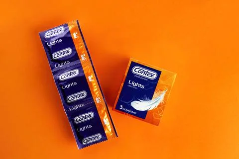 Packed condoms contex lie on an orange background Stock Photos