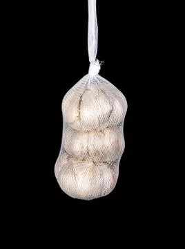 Packed garlic in a net isolated on a black background. Stock Photos