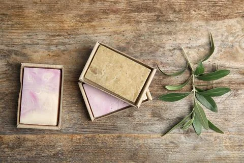 Packed handmade soap bars and olive twig on wooden table, top view Foto stock