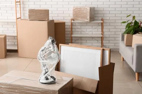 Packed moving boxes and household items in a room, relocation and new home co Stock Photos