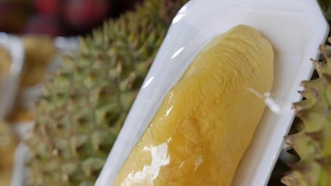 Packed portion of durian fruit displayed beside whole durian fruits with Stock Footage 331205788