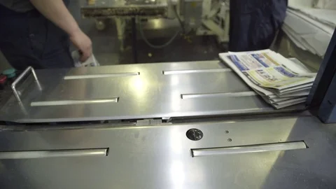 Packer puts stack of newspapers in wrapping paper packaging indoors Stock Footage 71317937