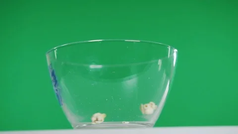 Packet of ready-made popcorn is poured into empty transparent bowl on table 動画素材 115925488