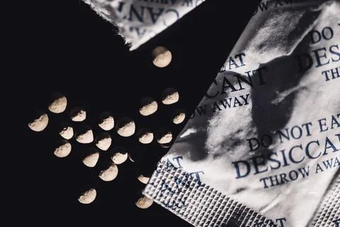 Packets of desiccant scattered on a dark surface Foto stock