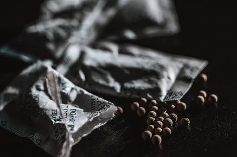 Packets of desiccant scattered on a dark surface Stock Photos