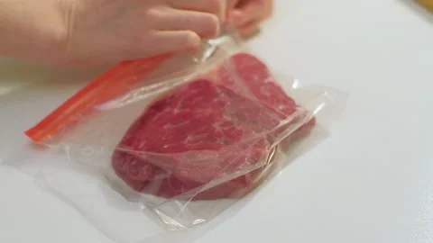 Packing beef meat in plastic bag for freezing at home. Cooking food concept 스톡 동영상 256624776