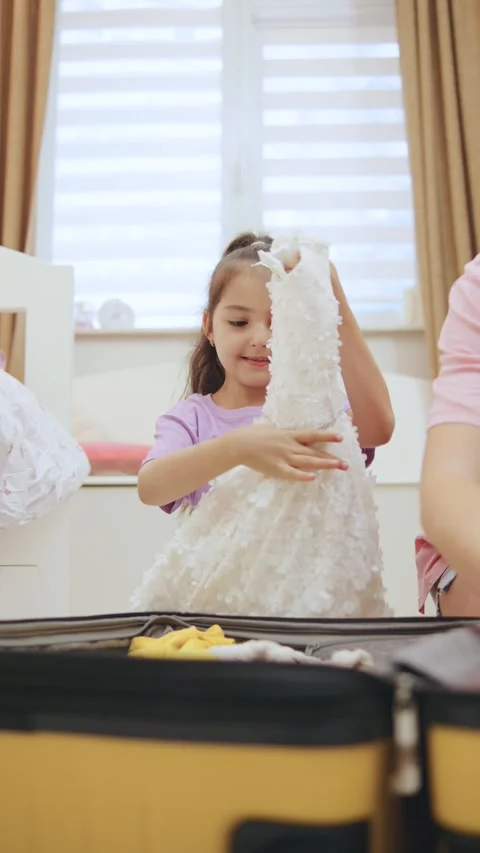 Packing clothes for a trip with a child in a bright room at a warm time of day Stock Footage 330746024
