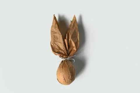 Packing an Easter egg in paper in the form of an Easter bunny. Stock Illustration