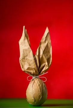 Packing an Easter egg in paper in the form of an Easter bunny. Stock Illustration