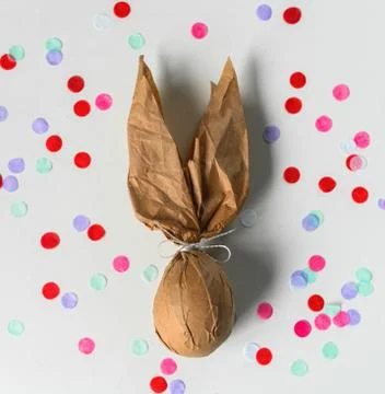 Packing an Easter egg in paper in the form of an Easter bunny. Stock Illustration