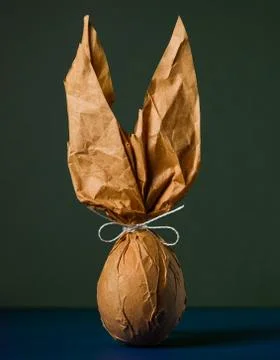 Packing an Easter egg in paper in the form of an Easter bunny. Stock Photos