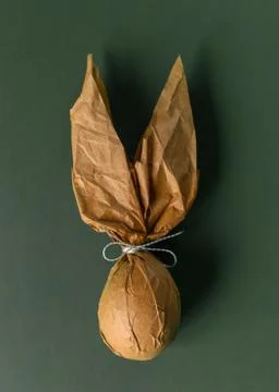 Packing an Easter egg in paper in the form of an Easter bunny. Stock Photos