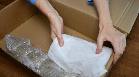 Packing up fragile tableware wrapped in plastic inside cardboard box Foto stock