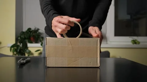 Packing a parcel at home, close up of hands preparing package for shipping in Stock Footage 316156444