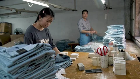 Packing Process of New Denim Jeans into Plastic Bags and Boxes Stock Footage 341548812