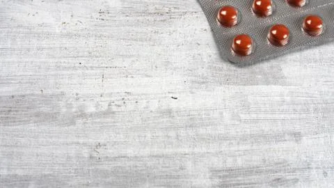 Packing with red pills on a gray structural background. Stock Photos