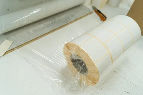 Packing rollers with self-adhesive white label in a transparent stretch film Stock Photos