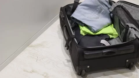 Packing the suitcase on the floor while someone throws the clothes inside it Stock Footage 140751031