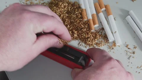 Packing tobacco into cigarette tubes using a hand tool. Cigarette Maker Video stock 302214021