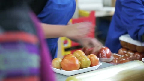 Packing tomatoes in food containers. A worker wraps up container with cling film Video stock 199486864
