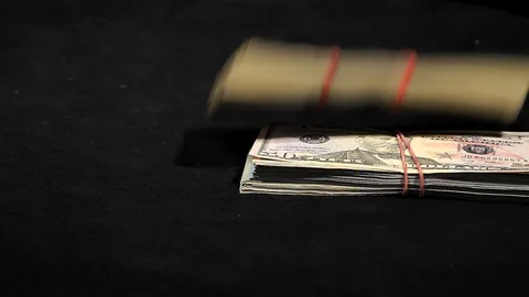 Packs of dollars falling on a black table close-up in slow motion. Stock Footage 129786556