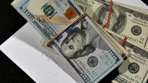 Packs of US dollars fall on a sheet of white paper on which. Stock Footage 129786688