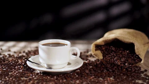 Packshot of White Coffee Cup with Hot Steam and Coffee Beans Around Stock Footage 303519181