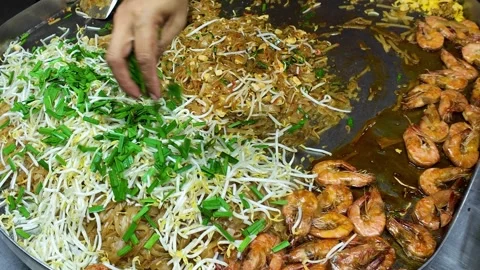 Pad Thai Cooking Close Up with Hand Adding Ingredients on Street Food Pan 4K Stock-Footage 332636064