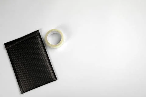 Padded envelope with bubble wrap and tape on light background, flat lay. Spac Stock Photos