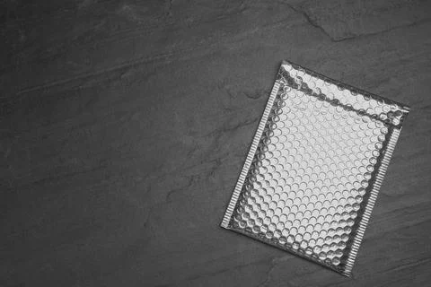 Padded envelope with bubble wrap on black background, top view. Space for tex Stock Photos