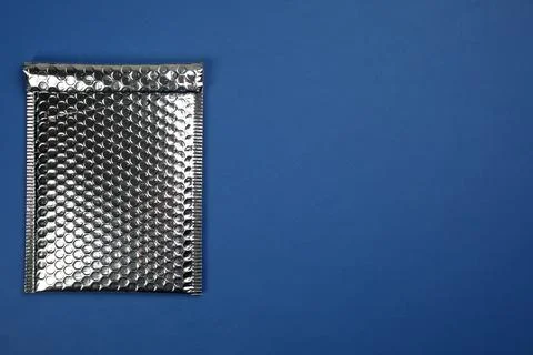 Padded envelope with bubble wrap on blue background, top view. Space for text Stock Photos