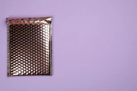 Padded envelope with bubble wrap on lilac background, top view. Space for tex Stock Photos