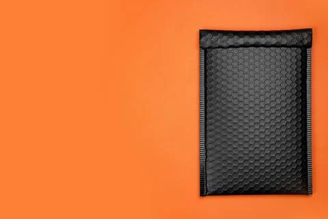 Padded envelope with bubble wrap on orange background, top view. Space for te Stock Photos