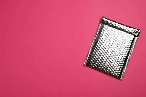 Padded envelope with bubble wrap on pink background, top view. Space for text Stock Photos