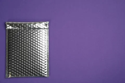 Padded envelope with bubble wrap on purple background, top view. Space for te Stock Photos