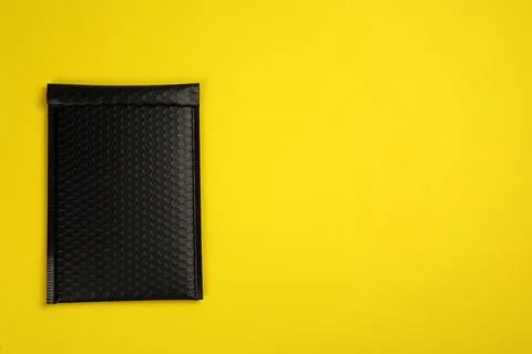 Padded envelope with bubble wrap on yellow background, top view. Space for te Stock Photos
